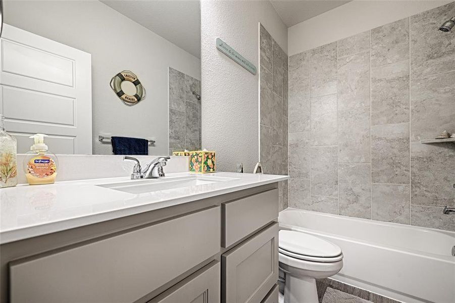 Full bathroom with tiled shower / bath combo, vanity, and toilet