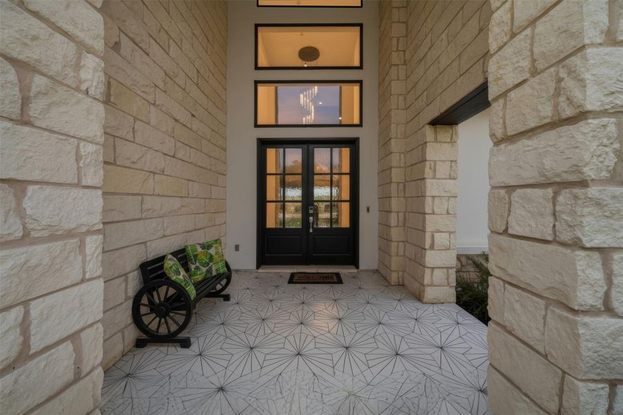 The property features a grand entrance with a double door entry, stone exterior walls, and patterned tile flooring