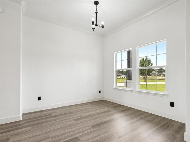 Spare room featuring an inviting chandelier, ornamental molding, and wood-type flooring