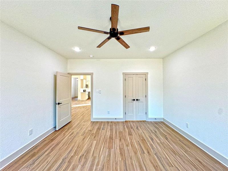 Unfurnished bedroom featuring light wood-style flooring, a textured wall, ceiling fan, a textured ceiling, and a closet