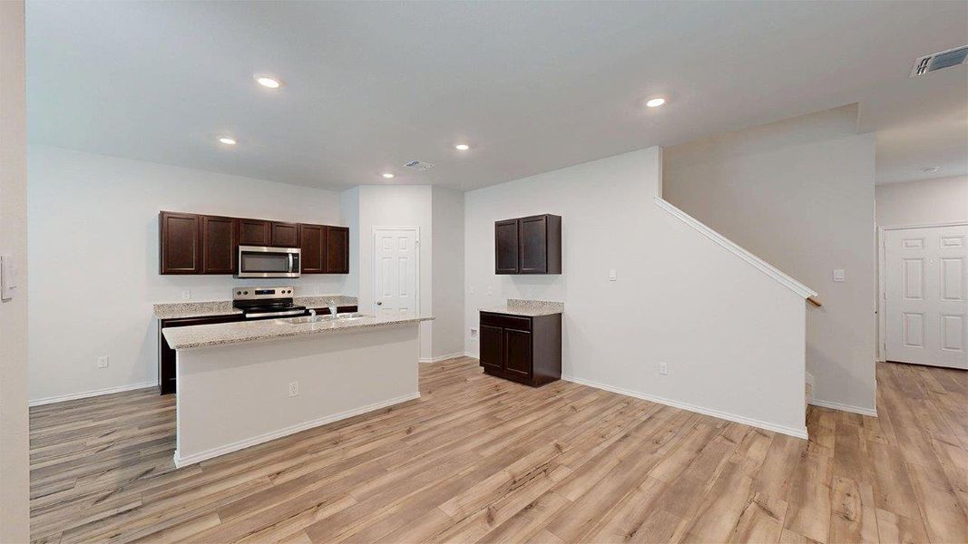 Kitchen featuring dark brown cabinetry, recessed lighting, a center island with sink, appliances with stainless steel finishes, and light wood-type flooring Kitchen featuring dark brown cabinetry, recessed lighting, a center island with sink, appliances with stainless steel finishes, and light wood-type flooring