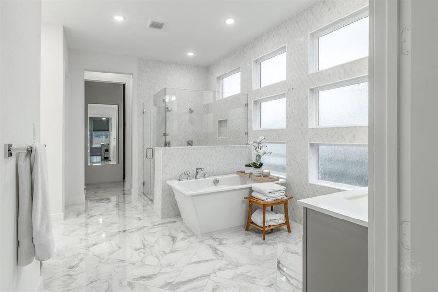 The Primary Bath is show-stopping.  Note the wall of privacy windows surrounded by imported tile.  This light-drenched space has a frameless double shower and free-standing tub.