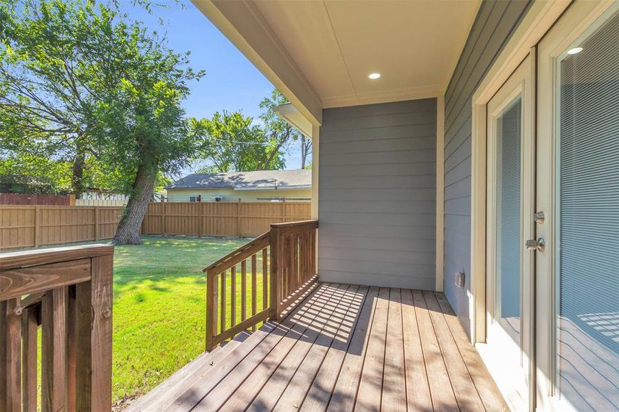Wooden terrace with a fenced backyard