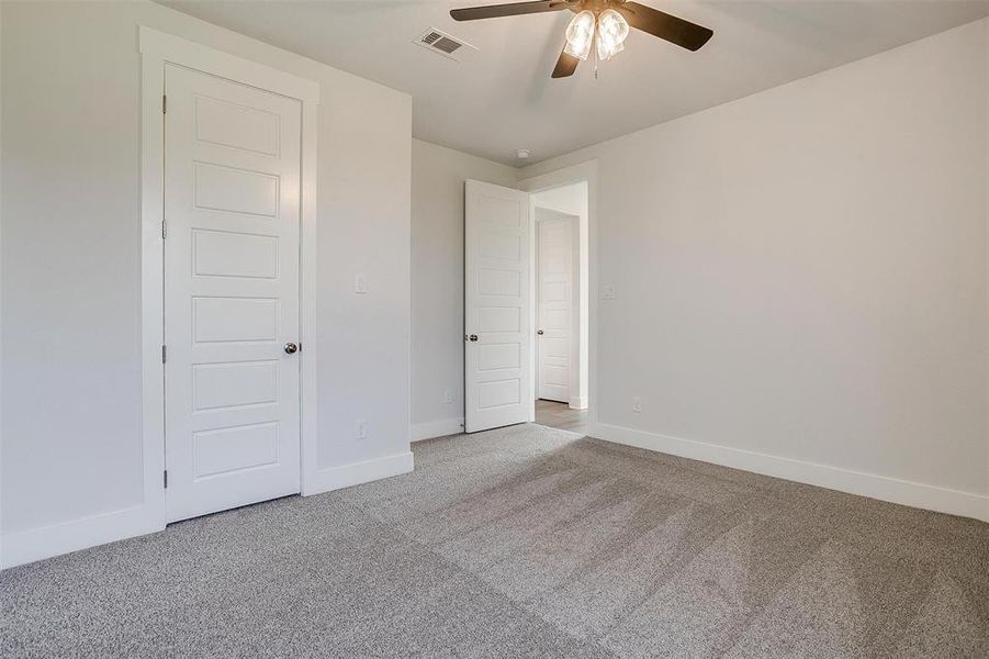 Unfurnished bedroom featuring ceiling fan and light colored carpet