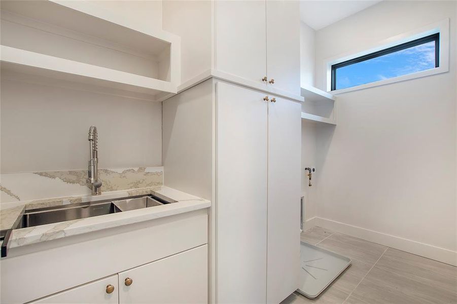 Laundry room featuring sink and light tile patterned floors