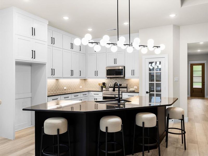 Kitchen featuring stainless steel appliances, dark countertops, light wood-style floors, and recessed lighting