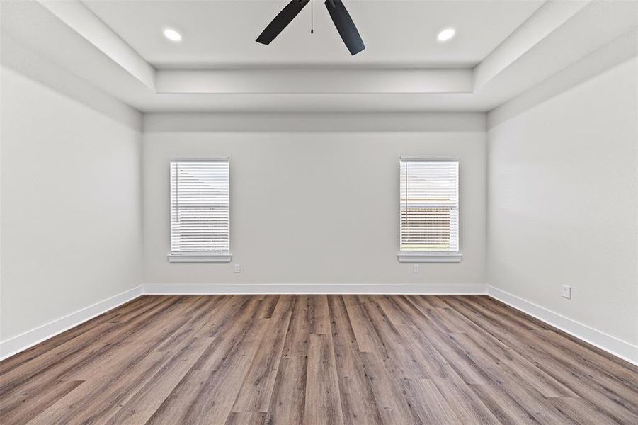 Unfurnished bedroom with wood finished floors, a tray ceiling, recessed lighting, and ceiling fan Unfurnished bedroom with wood finished floors, a tray ceiling, recessed lighting, and ceiling fan