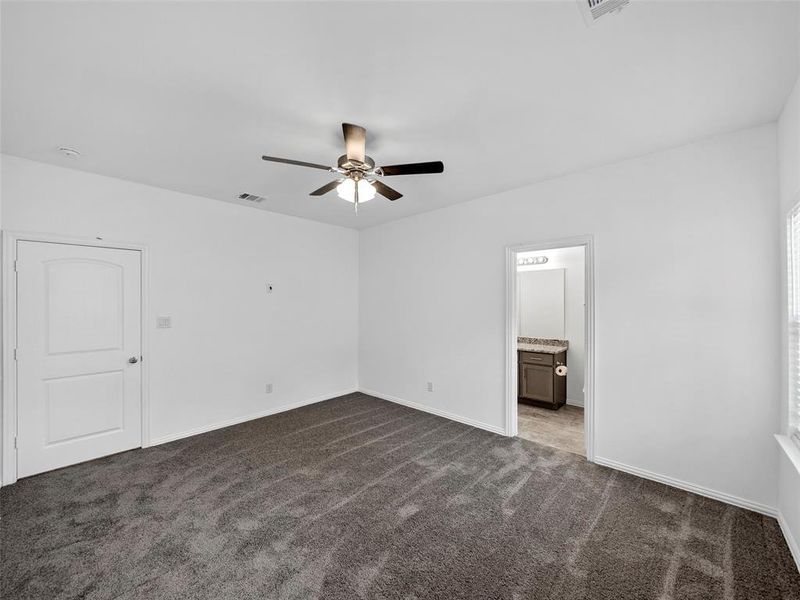 Unfurnished room featuring dark colored carpet and ceiling fan