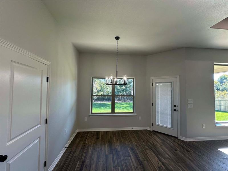 Unfurnished dining area with dark wood-type flooring and a chandelier Unfurnished dining area with dark wood-type flooring and a chandelier