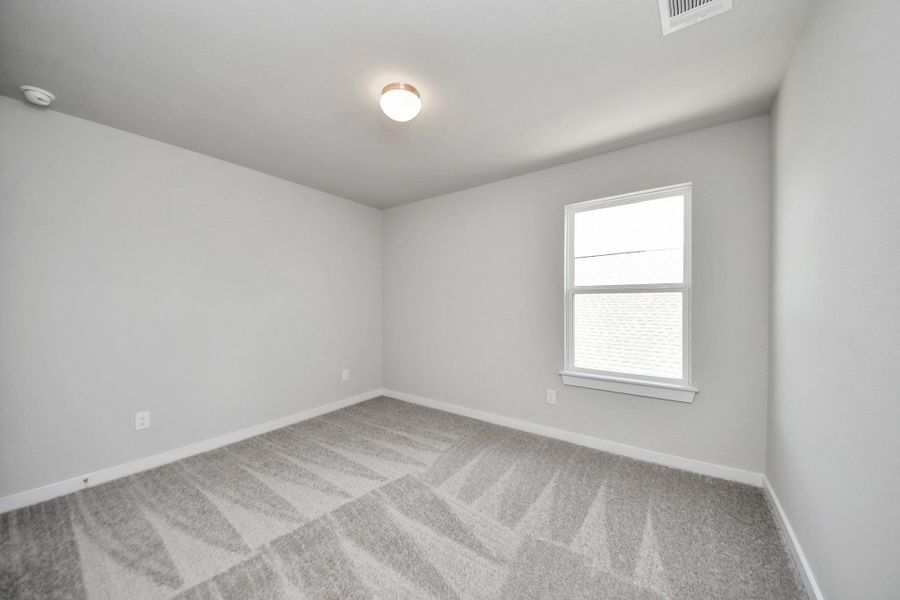 Secondary bedroom features plush carpeting, large windows that let in plenty of natural light, bright paint, and spacious closets. Sample photo of completed home with similar floor plan. Actual colors and selections may vary.