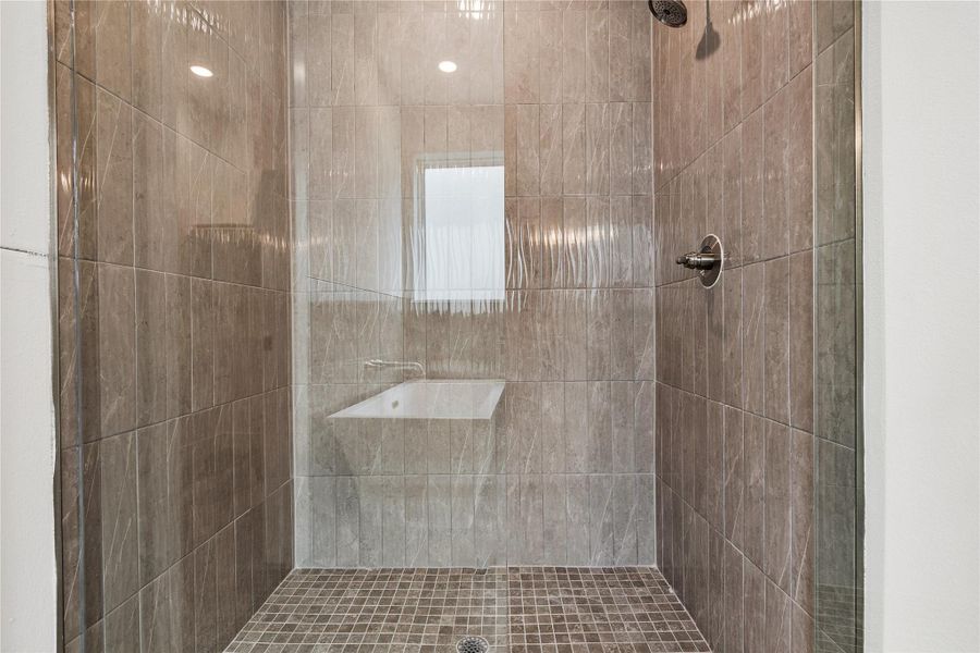 A spacious, glass-enclosed shower offers modern tiling and a built-in bench.