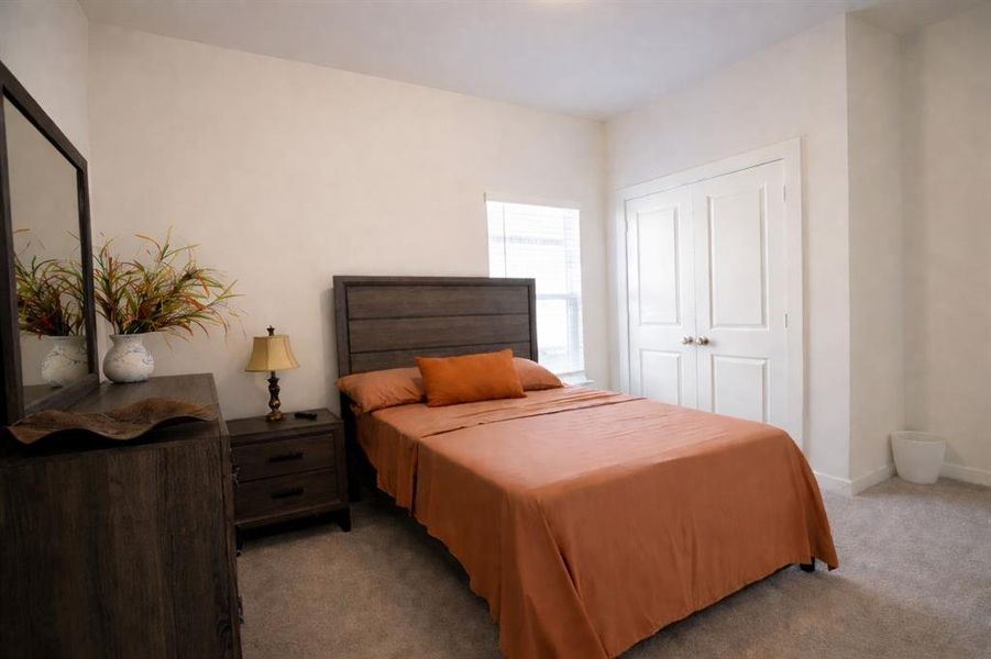 Bedroom featuring neutral carpeting, light-toned wall paint, a double-door closet with paneling, and a window with blinds