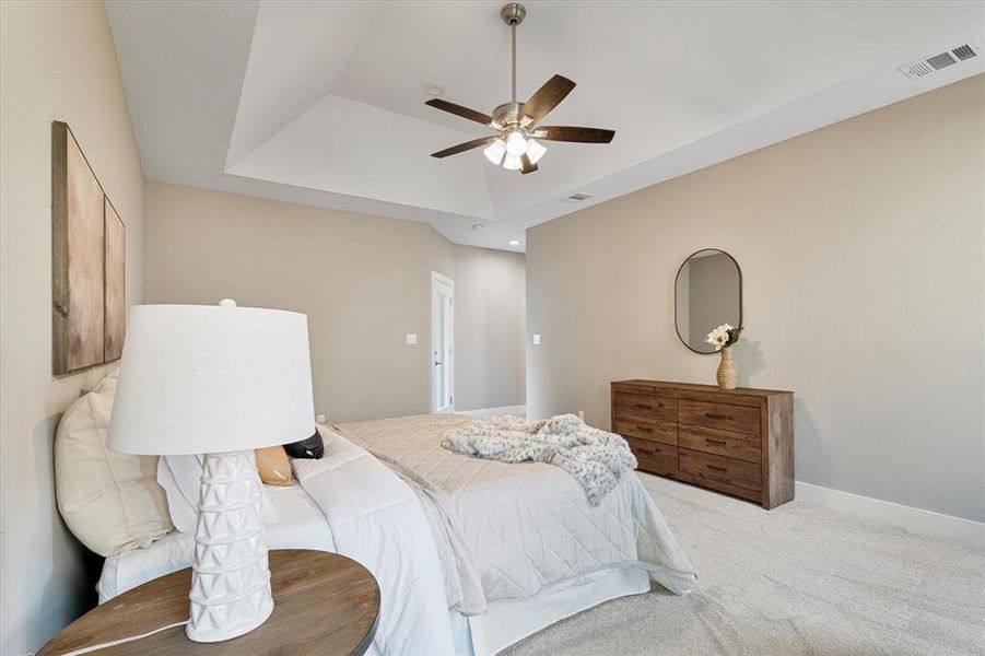Bedroom with ceiling fan, light colored carpet, and a tray ceiling Bedroom with ceiling fan, light colored carpet, and a tray ceiling