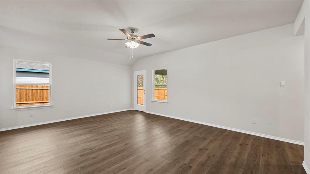 Spacious room featuring wood-finish flooring, white baseboards, and bright white walls Spacious room featuring wood-finish flooring, white baseboards, and bright white walls