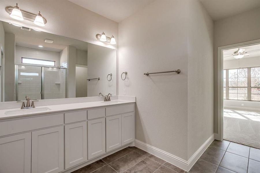 Bathroom featuring plenty of natural light, double vanity, a stall shower, and dark tile patterned floors