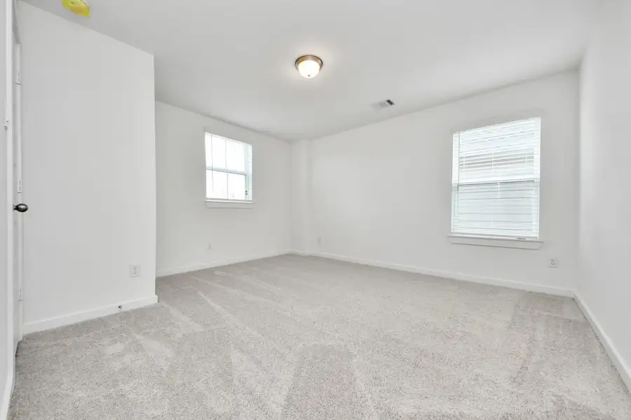 Secondary bedroom features plush carpeting, large windows that let in plenty of natural light, bright paint, and spacious closets.