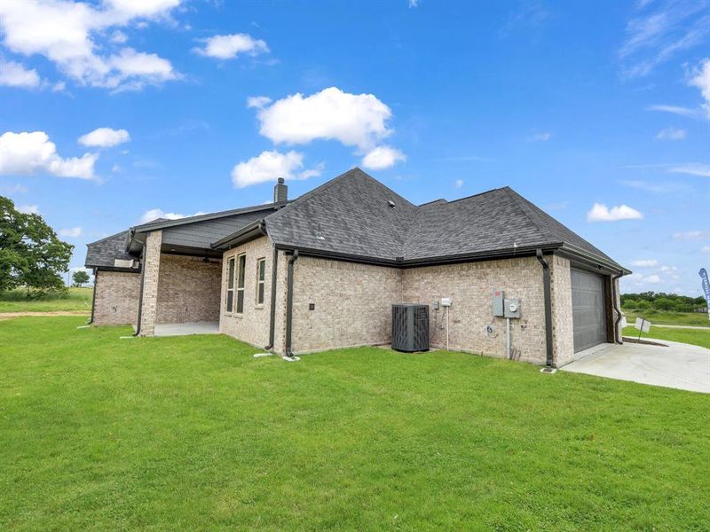 Rear view of house with a patio, a lawn, an attached garage, and brick siding