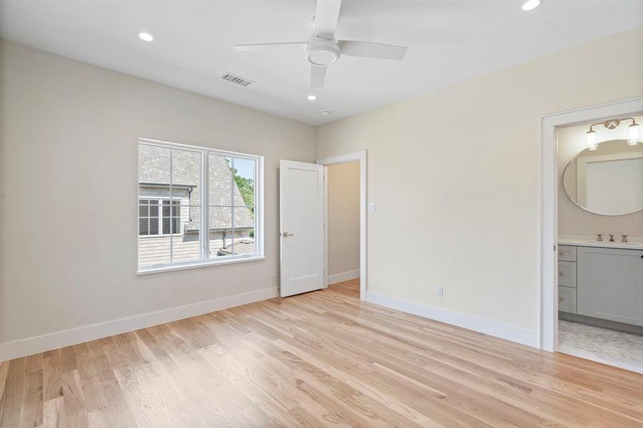 Unfurnished bedroom with sink, ensuite bath, light wood-type flooring, and ceiling fan