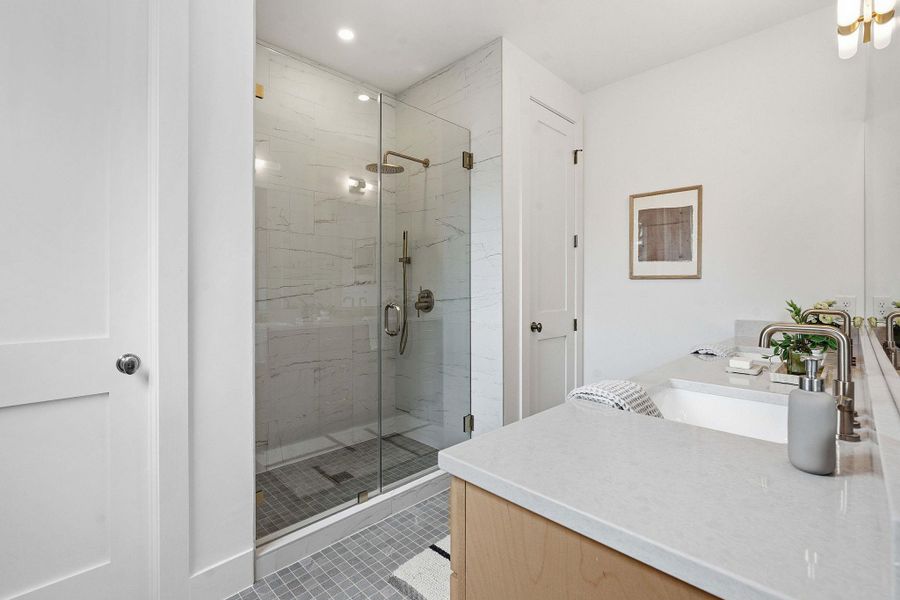 Glass-enclosed shower with white marble-style tile surround and rainfall showerhead