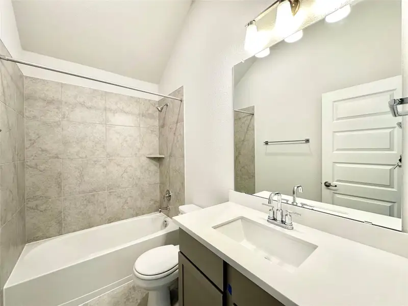 Full bath featuring shower / bath combination, vanity, and lofted ceiling Full bath featuring shower / bath combination, vanity, and lofted ceiling