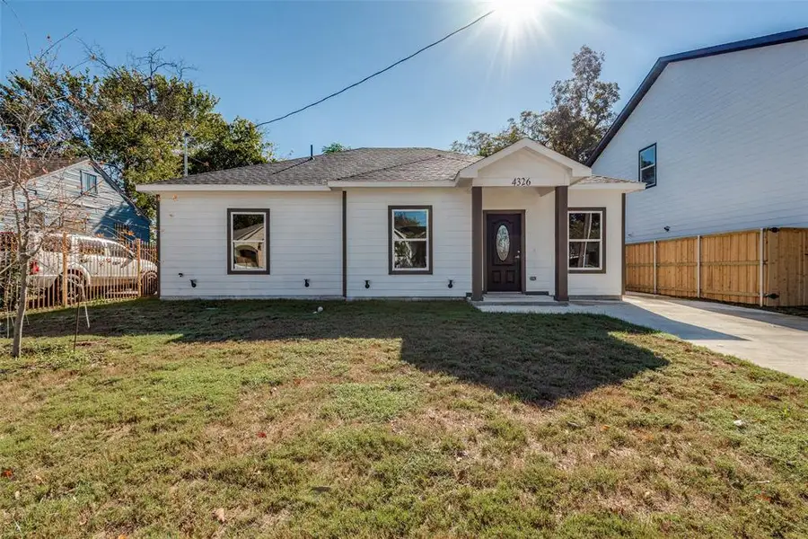 White house with siding and dark brown trim, concrete driveway, and a front lawn