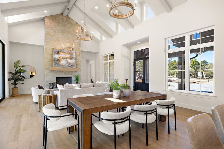 Dining space featuring beam ceiling, a fireplace, light wood-style flooring, an inviting chandelier, and baseboards