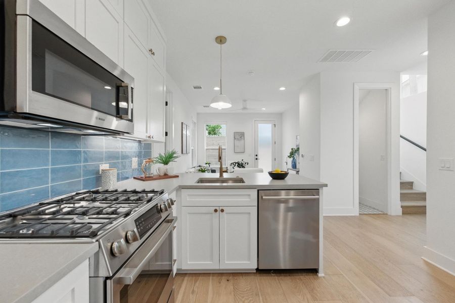 Kitchen with stainless steel appliances, white cabinets, tasteful backsplash, light wood-style flooring, and recessed lighting Kitchen with stainless steel appliances, white cabinets, tasteful backsplash, light wood-style flooring, and recessed lighting