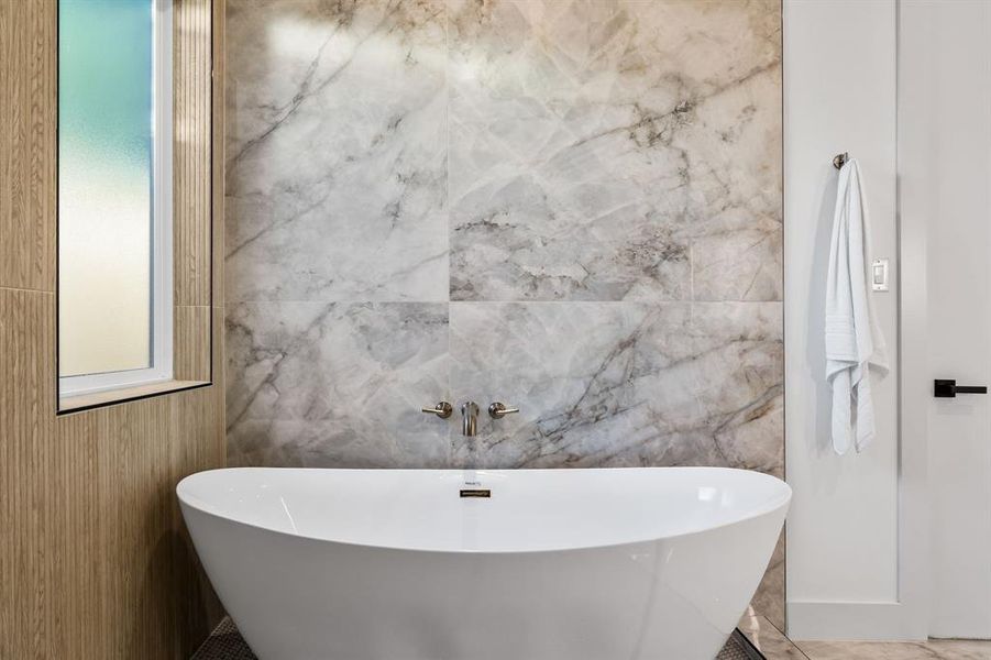 Bathroom with tile patterned flooring, a washtub, and tile walls