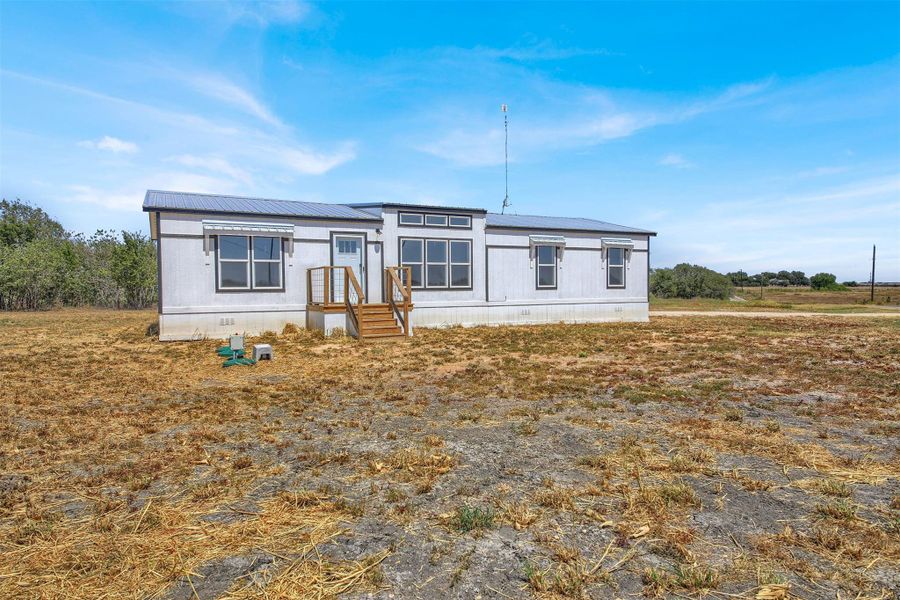 A manufactured home sits on an open lot beneath clear blue skies.