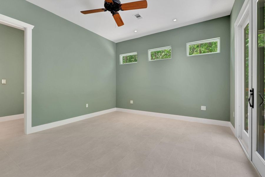 Primary bedroom with unique transom windows, neutral tones, and private patio access
