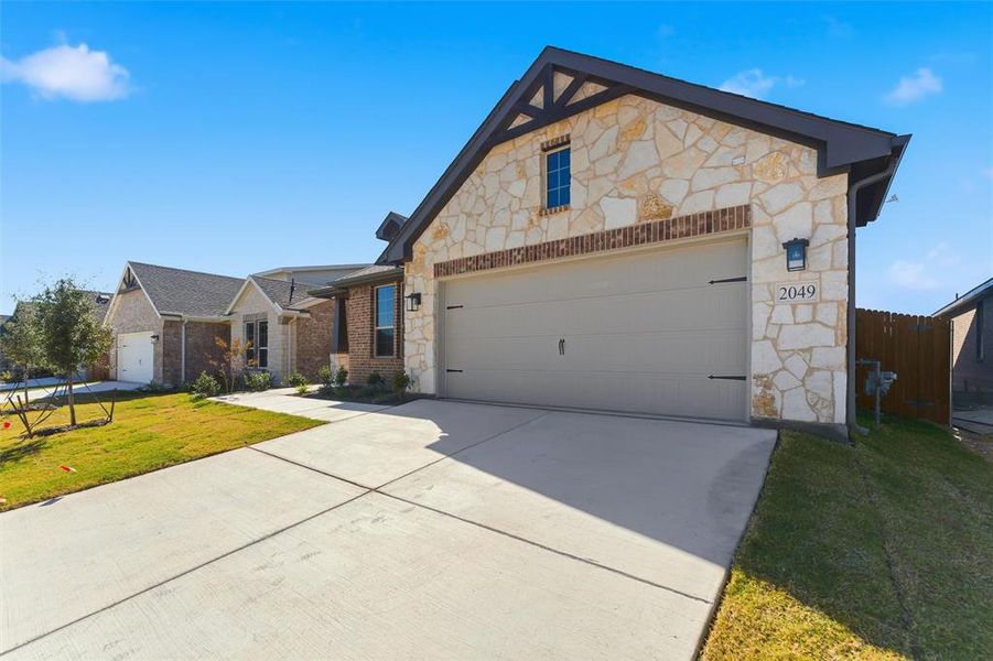 View of front of property featuring stone siding and driveway