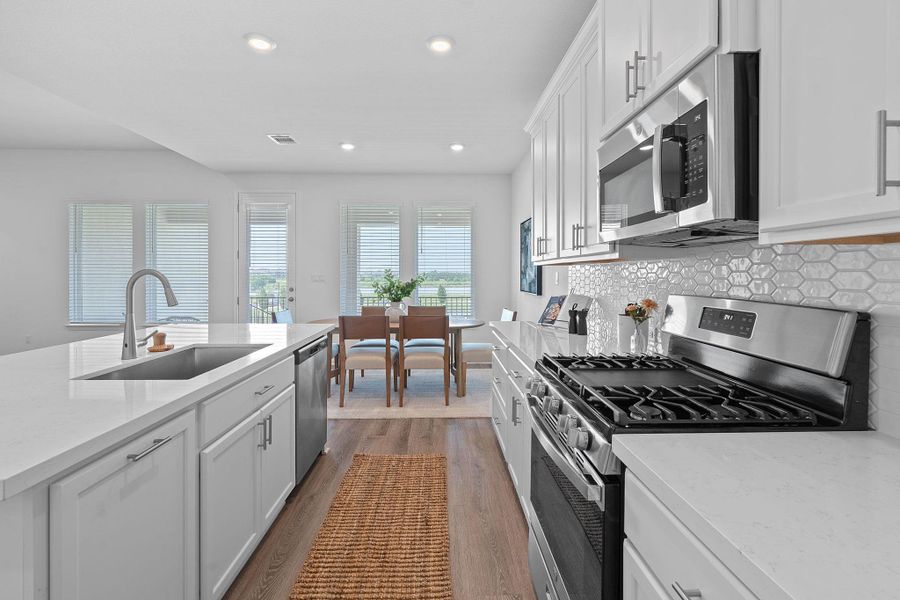 Kitchen with appliances with stainless steel finishes, a sink, dark wood-style flooring, recessed lighting, and decorative backsplash