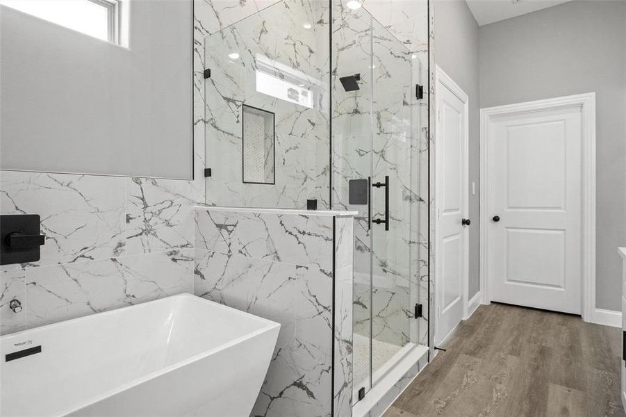 Bathroom featuring a soaking tub, a marble finish shower, and wood finished floors Bathroom featuring a soaking tub, a marble finish shower, and wood finished floors