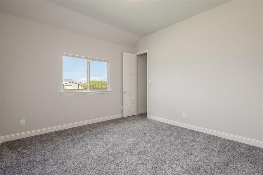 Carpeted empty room with vaulted ceiling