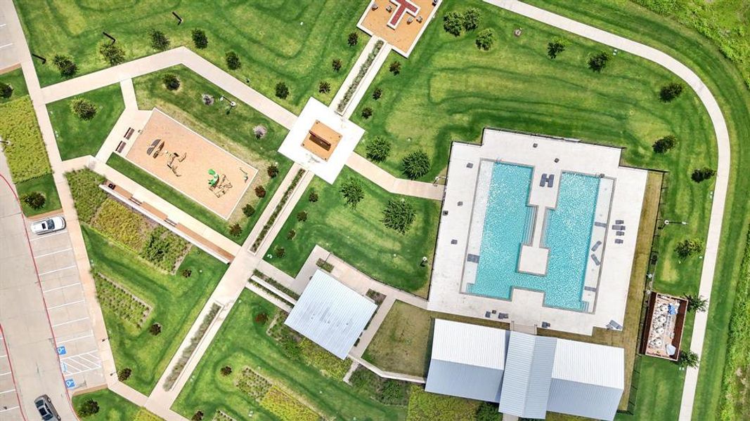 Community amenities featuring a large swimming pool, multiple recreational sand areas, a building with a metal roof, extensive paved pathways, and manicured green spaces Community amenities featuring a large swimming pool, multiple recreational sand areas, a building with a metal roof, extensive paved pathways, and manicured green spaces