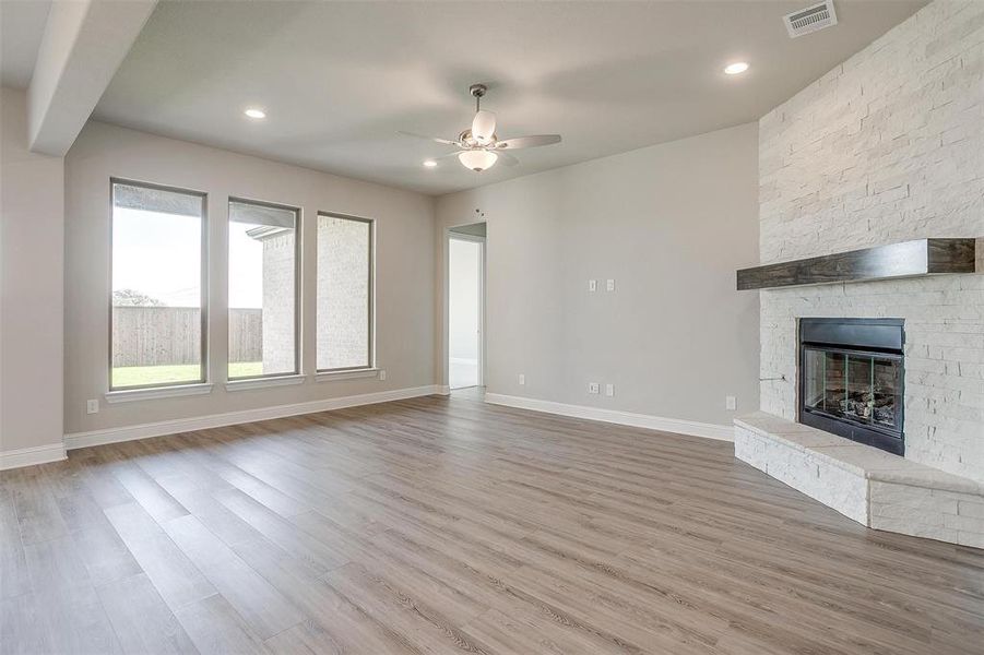 Unfurnished living room featuring ceiling fan, wood-type flooring, and a fireplace