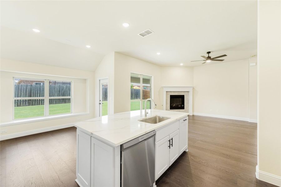 Kitchen island with white cabinets and quartz countertop open to living room with fireplace and hardwood floors Kitchen island with white cabinets and quartz countertop open to living room with fireplace and hardwood floors