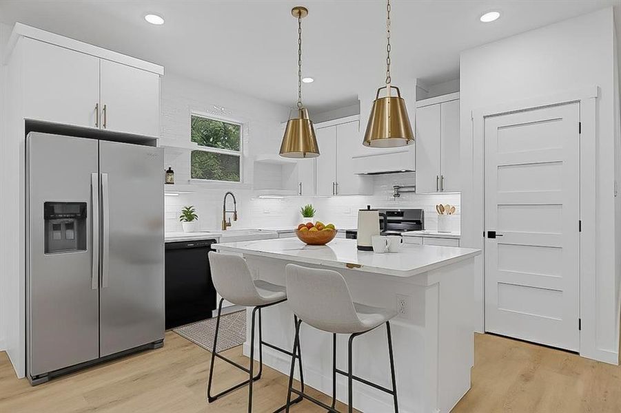 Kitchen featuring white cabinetry, stainless steel fridge with ice dispenser, a breakfast bar, tasteful backsplash, and a kitchen island Kitchen featuring white cabinetry, stainless steel fridge with ice dispenser, a breakfast bar, tasteful backsplash, and a kitchen island