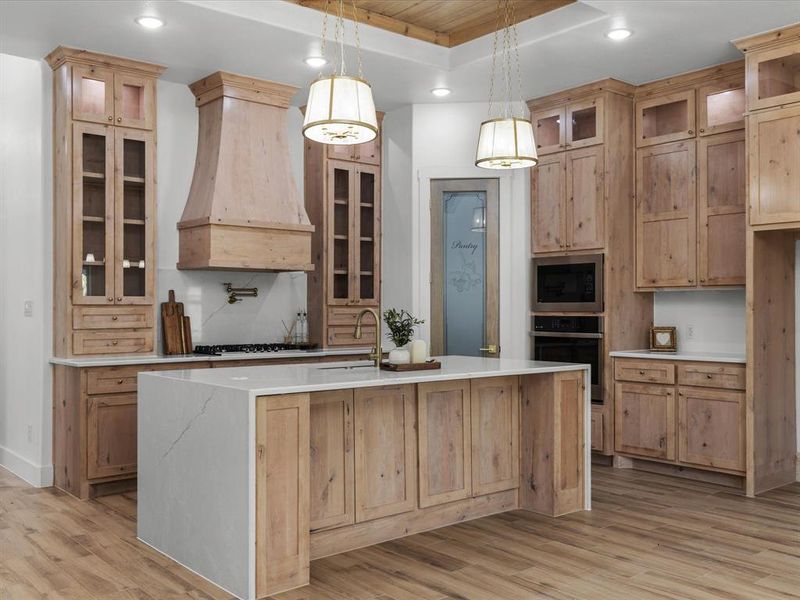 Kitchen with glass insert cabinets, recessed lighting, light stone counters, oven, and pendant lighting