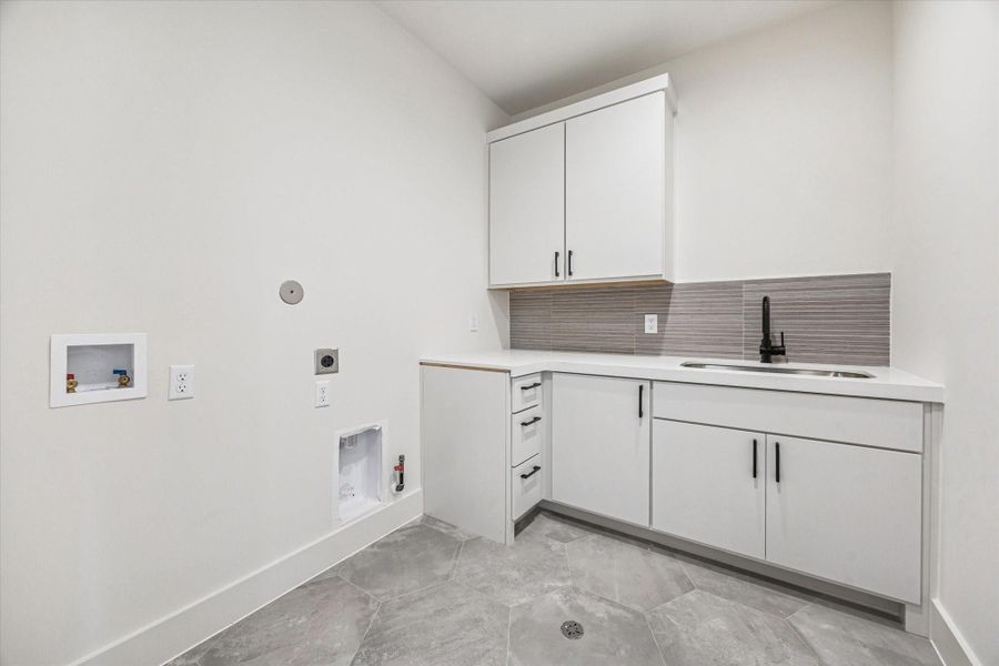 Spacious laundry room with a sink, storage, hexagon floor tile and white quartz countertop.