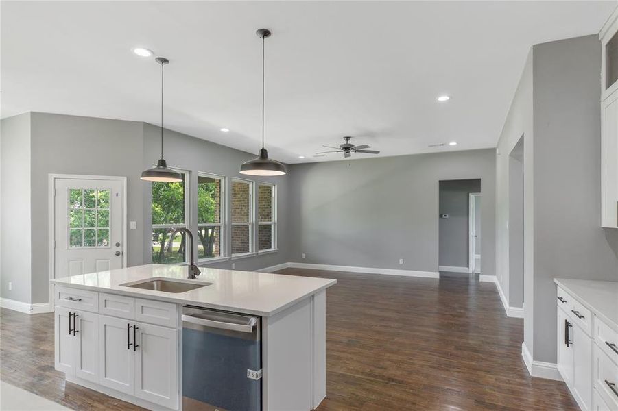 Kitchen with white cabinetry, hanging light fixtures, dishwasher, recessed lighting, and light stone counters Kitchen with white cabinetry, hanging light fixtures, dishwasher, recessed lighting, and light stone counters
