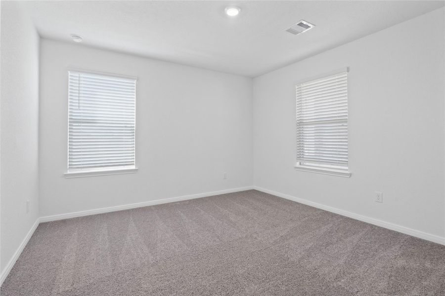 Secondary bedroom, pictured here, features plush carpeting, neutral paint tones, recessed lighting, large windows with privacy blinds, and a spacious closet.