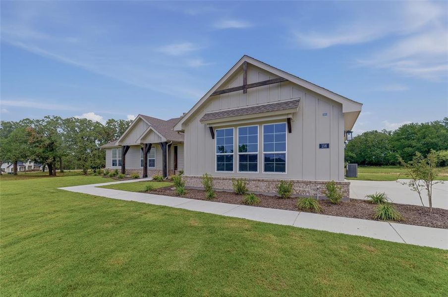 Board and batten siding exterior with a stone accent foundation, multiple gables, a covered front porch with dark wood pillars, and a concrete driveway
