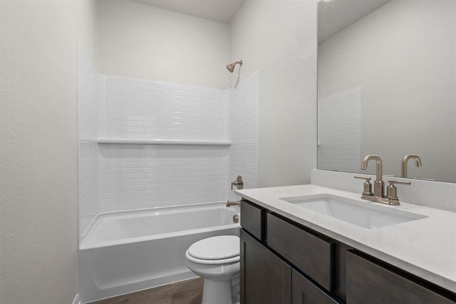 Full bathroom with  shower combination, vanity, dark wood-type flooring, and a textured wall