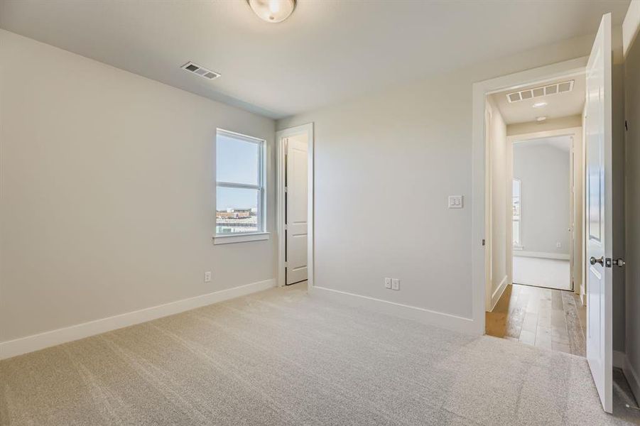 Unfurnished bedroom with light colored carpet and baseboards