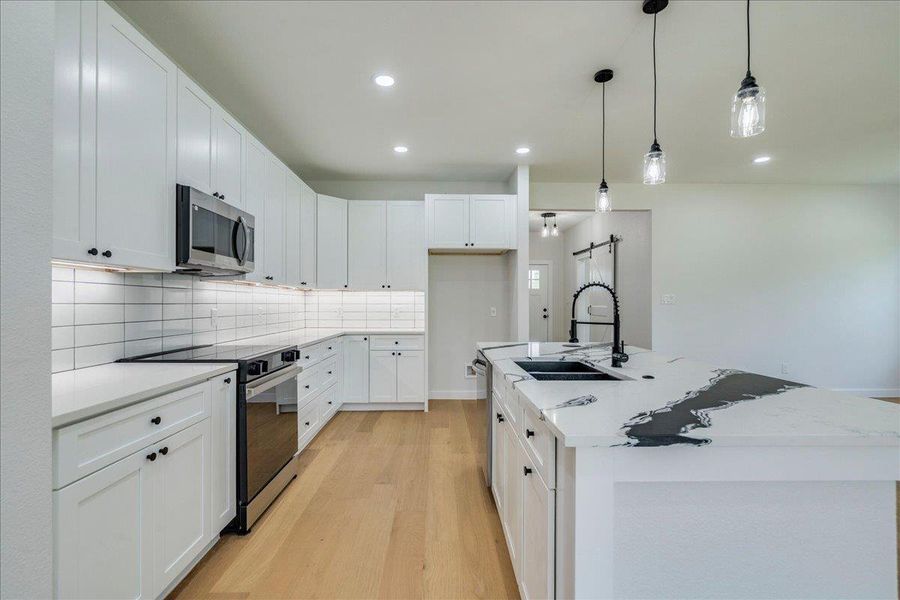 A sleek, contemporary kitchen w/ white cabinetry and a striking black and white island.