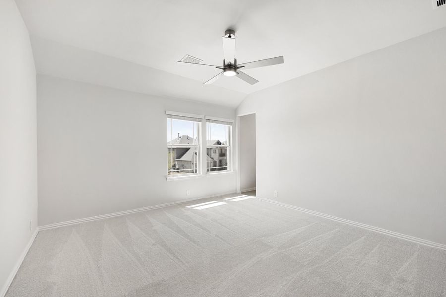 Empty bedroom with vaulted ceiling, ceiling fan, carpet flooring, and a window with neighborhood view