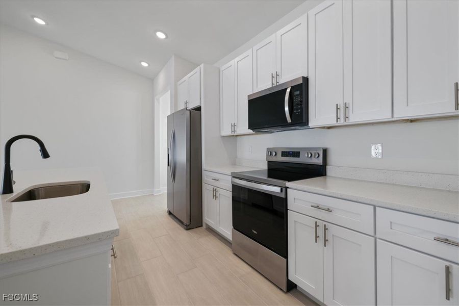 Kitchen featuring stainless steel appliances, light stone countertops, white cabinetry, and recessed lighting Kitchen featuring stainless steel appliances, light stone countertops, white cabinetry, and recessed lighting