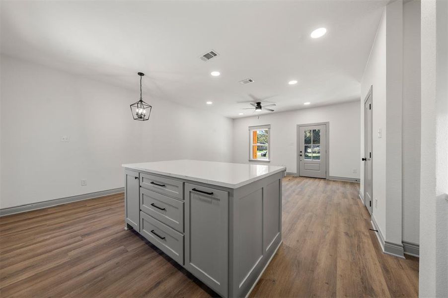 Kitchen featuring gray cabinets, pendant lighting, a center island, recessed lighting, and dark wood-type flooring