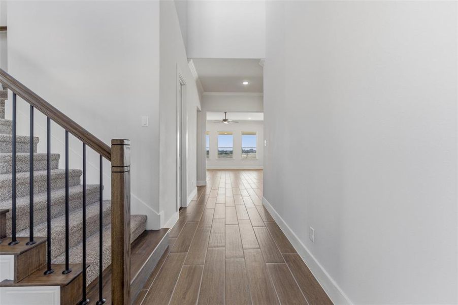 Hallway with wood finish floors, stairway, and ornamental molding